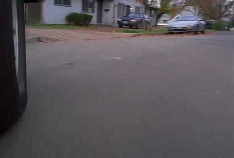 Front-wheel mount POV of car pulling into a residential driveway and stopping Stock Footage 86885881