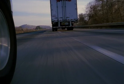 Front-wheel mount POV of vehicle passing a truck on the freeway Stock Footage 86885877