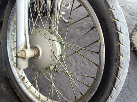 The front wheel of an old, worn and dirty motorbike in a workshop Stock Photos