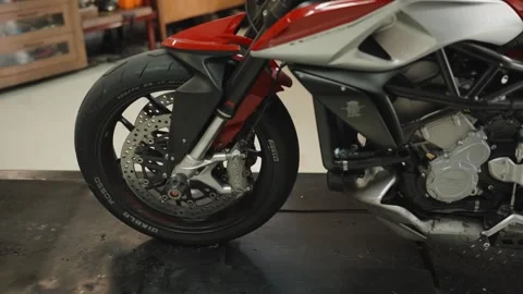Front wheel of a red motorcycle raised on a shop lift Stock Footage 346252053