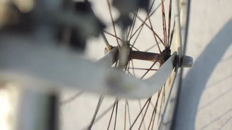 Front wheel of a rusty bicycle spinning with shadow reflected on the street. Stock Footage 144910188
