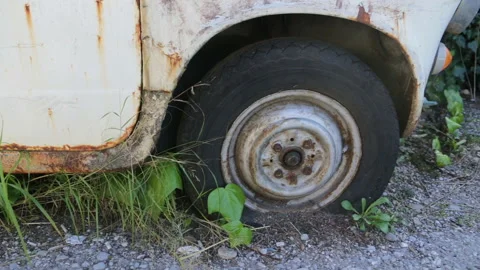 Front wheel well with flat and ruptured tire on rusty abandoned and derelict car Stock Footage 167538000