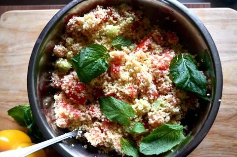 In front of a window. Couscous with mint, tomato, lemon and olive oil. Stock Photos
