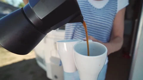 Frontal shot pouring coffee while camping from black italian espresso machine Vídeos de archivo 204123769