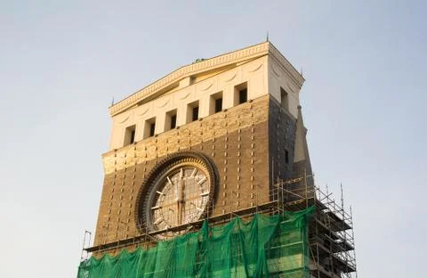 Frontal side of clock tower with dial. Scaffold around building Stock Photos