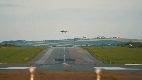 A frontal video of an airport landing strip with a plane, going down, landing Stock Footage
