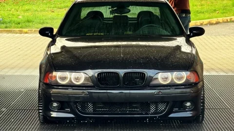Frontal view of black BMW being washed at a self-service car wash station Stock Footage 326305542