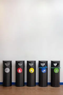 Frontal View of Five Color-Coded Recycling Bins Aligned on a Blue Floor Against Stock Photos
