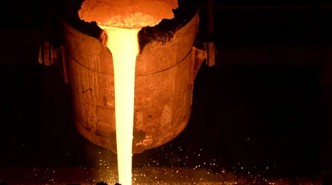 Frontal view of molten metal flowing from smelter bin Stock Footage