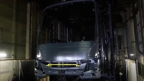 Frontal view of a primed bus shell moving through a dark industrial Stock Footage 332141932