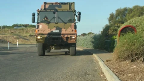 Frontal view of two army trucks driving along winding road 動画素材 141245684
