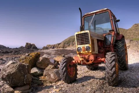 Frontside of Old, rusty tractor on a pebble beach 写真素材