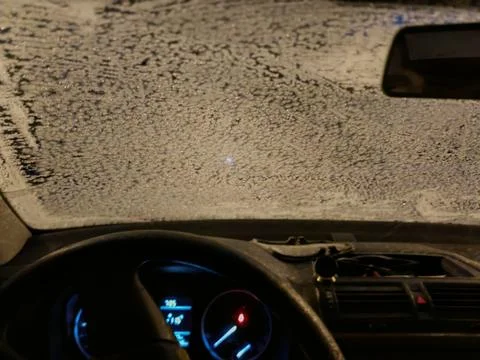 Frost-covered car windshield viewed from inside at night, wide view Stock Photos