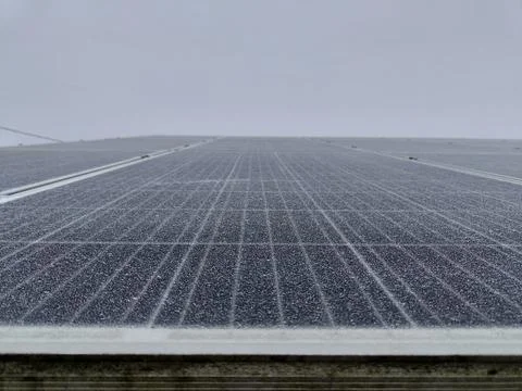 Frost-covered solar panel surface on a cloudy winter day Stock Photos