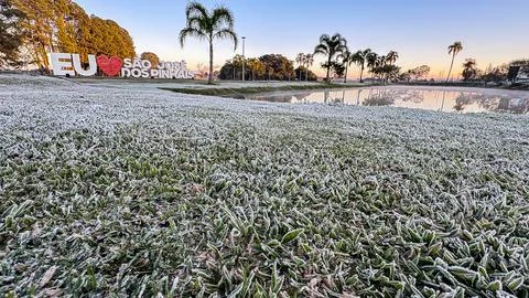 Frost on the grass, in the foreground, with focus on the ice and in the backg Stock Photos