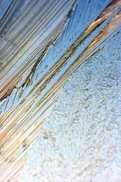 Frost ice patterns on clear glass with color bokeh winter background Stock Photos