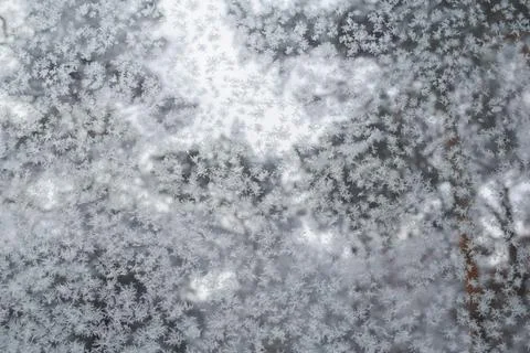 Frost patterns and delicate snow crystals on a glass window pane 写真素材