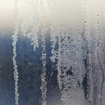 Frost patterns cling to a window pane. Tiny ice crystals form intricate des.. Stock Photos