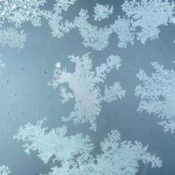Frost patterns cling to a window pane. Tiny ice crystals form intricate des.. Stock Photos