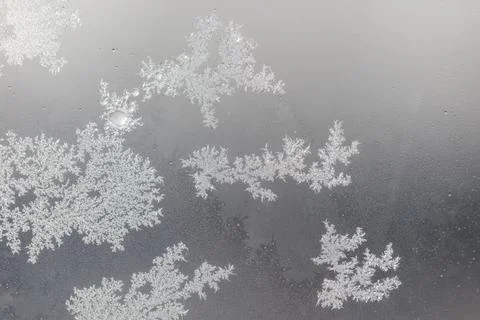 Frost patterns cling to a window pane. Tiny ice crystals form intricate des.. Stock Photos