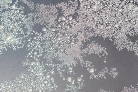 Frost patterns cling to a window pane. Tiny ice crystals form intricate des.. Stock Photos