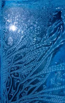 Frost patterns on frozen window as a symbol of Christmas wonder. Stock Photos