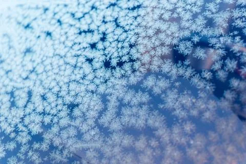 Frost patterns on a glass window creates winter themed patterns with a blue w Stock Photos