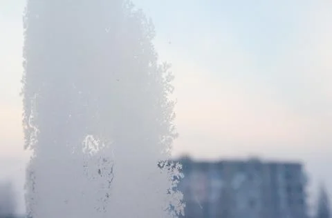 Frost structure on window against the background of city during winter day. Stock Photos