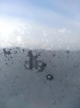 Frost structure on window against the background of city during winter day. Stock Photos