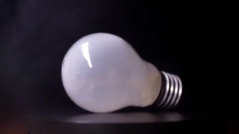 Frosted Light Bulb Lying Sideways With Smoke Clouds On Black Background 库存影片 330109926