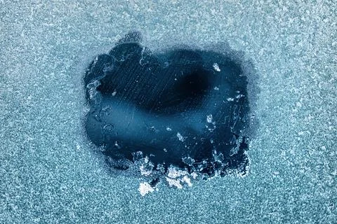 Frosted Window With a Clear Patch Revealing an Icy Blue Background During a.. Stock Photos