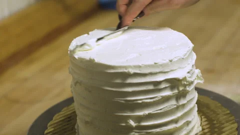 Frosting is spread on the top of a cake Stock Footage 130588130
