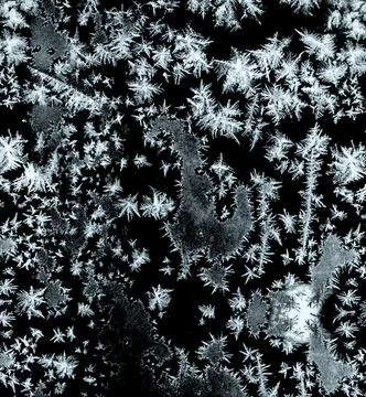 Frostwork pattern ice crystals on black background. Dark surface with abstrac Stock Photos