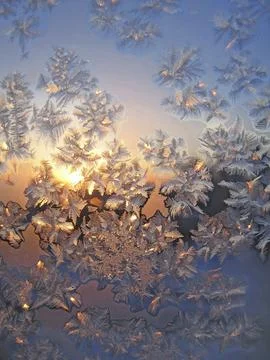 Frosty natural pattern and sun on winter window Stock Photos