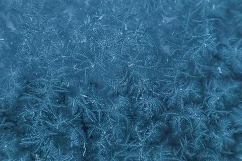 Frosty pattern in blue tones on window glass on a winter day Stock Photos