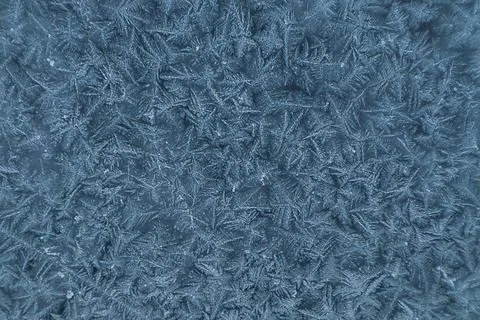 Frosty pattern on a window in blue tones on a frosty winter day Stock Photos