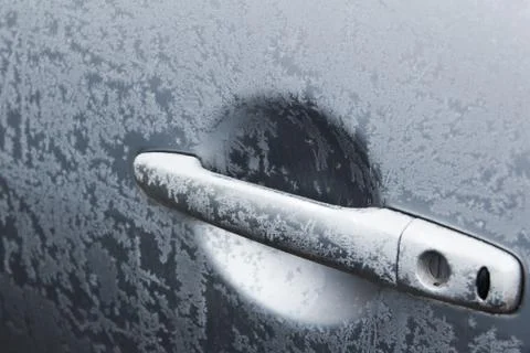 Frosty patterns on the door handle of a gray car. Stock Photos