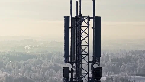 Frosty telecom cell tower with antenna panels rising above a misty winter Stock Footage 331488512
