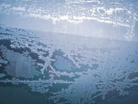 A frosty window with a blue sky in the background.  Stock Photos