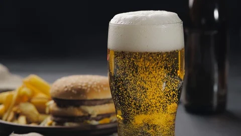 Frothing beer in glass with bubbles coming out, white foam on top. Blurred Stock Footage 128888607