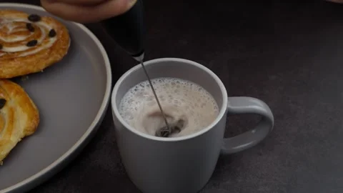 Frothing a cup with milk and coffee dark background Cinnamon rolls Stock Footage 278608798