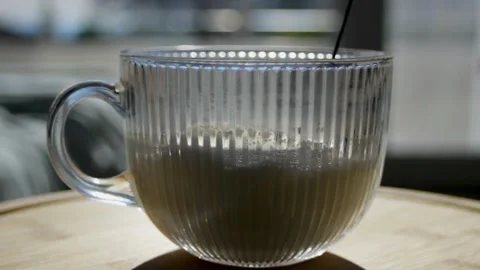 Frothing milk with a hand whisk. Preparing the milk before pouring in black Stock Footage 297462140