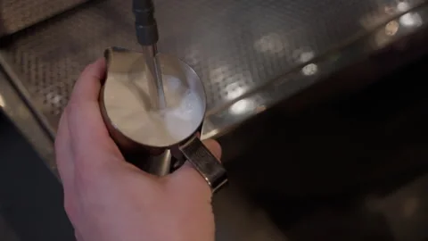 Frothing milk in pitcher creates velvety texture closeup Видео 297351621
