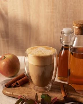 Frothy apple maple latte in a transparent glass sits on a wooden board, Stock Photos