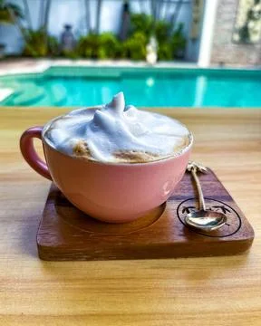 Frothy Cappuccino in Pink Cup by the Poolside Stock Photos