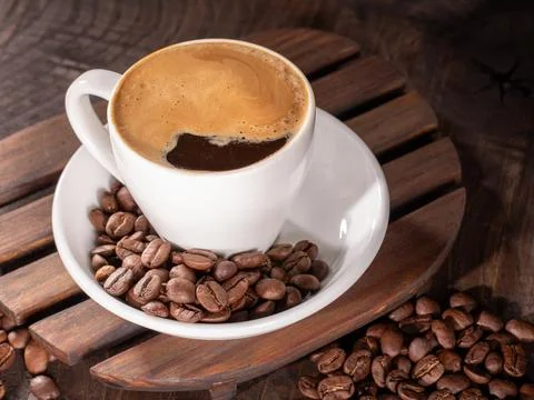 Frothy coffee cup elegantly framed by a border of coffee beans Stock Photos
