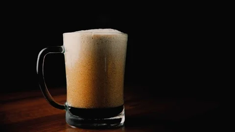 Frothy dark beer in Glass Stock Footage 88705856