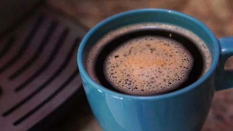 Frothy, invigorating freshly brewed morning coffee is spinning in a blue glass,  Video stock 112685969