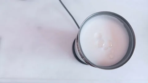 Frothy milk in the milk frothing machine in the kitchen taken from top angle Stock Footage 130981868