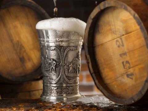 Frothy mug of beer set in a rustic cellar Stock Photos